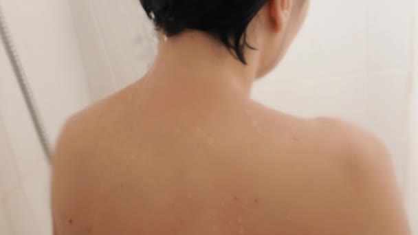 Femme nue prend une douche. Femme se lave les cheveux courts avec de l'eau. Vidéo au ralenti dans la salle de bain blanche . — Video