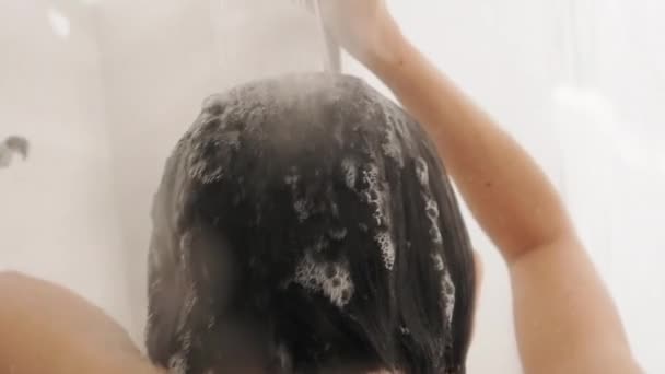 Una donna nuda si fa una doccia. Donna lava i capelli corti con lo shampoo. Video al rallentatore in bagno bianco . — Video Stock