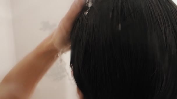 Una donna nuda si fa una doccia. Donna lava i capelli corti con lo shampoo. Video al rallentatore in bagno bianco . — Video Stock