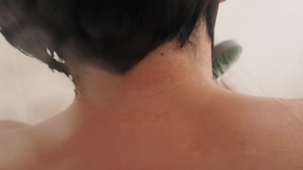 Una donna nuda si fa una doccia. La donna lava i capelli corti con acqua. Video al rallentatore in bagno bianco . — Video Stock