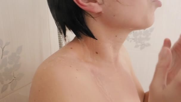 Гола жінка приймає душ. Жінка миє коротке волосся водою. Повільне відео руху у білій ванній кімнаті . — стокове відео