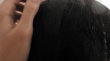 Çıplak kadın duş alıyor. Kadın kısa saçlarını suyla yıkıyor. Beyaz banyoda yavaş çekim videosu.