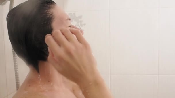 Nackte Frau duscht. Frau wäscht ihre kurzen Haare mit Wasser. Zeitlupenvideo im weißen Badezimmer. — Stockvideo