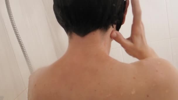 Femme nue prend une douche. Femme se lave les cheveux courts avec de l'eau. Vidéo au ralenti dans la salle de bain blanche . — Video