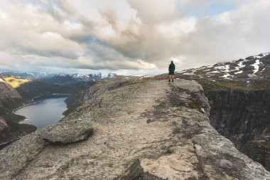 Turist Trol dilinde tek başına duruyor. Norveç 'in Vestland ilçesinin ünlü doğal simgesi Trolltunga. Seyahat tutkusu. Dağlarda gün doğumu.  