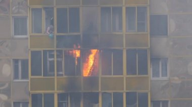 ODINTSOVO, RUSSIA - 25 Nisan 2020. Konut binasında yangın. Alevler balkon penceresinden dışarı fırladı. Kadın söndürmeye çalışıyor, suyla alev alıyor. Yavaş çekim.
