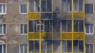 Konut binasında yangın. Alevler balkon penceresinden dışarı fırladı. İtfaiyeciler alevleri yerden söndürür. Yavaş çekim.