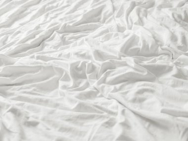 Beyaz buruşuk çarşaflı arka plan. Kopyalama alanı olan yumuşak çarşaflar. Konforlu evin yatak odasında yapılmamış yatak.