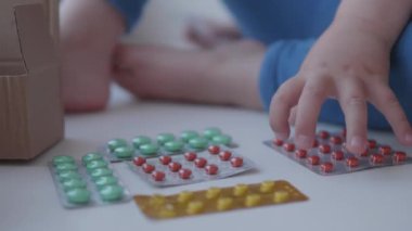 Bebek pencere eşiğinde oturur ve ebeveyn kontrolü olmadan ilaçlarla oynar. Küçük çocukla tehlikeli bir durum. İlaçlar çocuk için ücretsiz olarak mevcuttur.