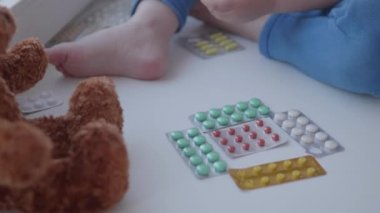 Bebek pencere eşiğinde oturur ve ebeveyn kontrolü olmadan ilaçlarla oynar. Küçük çocukla tehlikeli bir durum. İlaçlar çocuk için ücretsiz olarak mevcuttur.