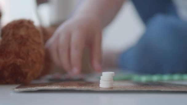 Tout-petit est assis sur le rebord de la fenêtre et joue avec des pilules de dispersion sans contrôle des parents. Situation dangereuse avec le petit garçon. Les médicaments sont disponibles gratuitement pour l'enfant.