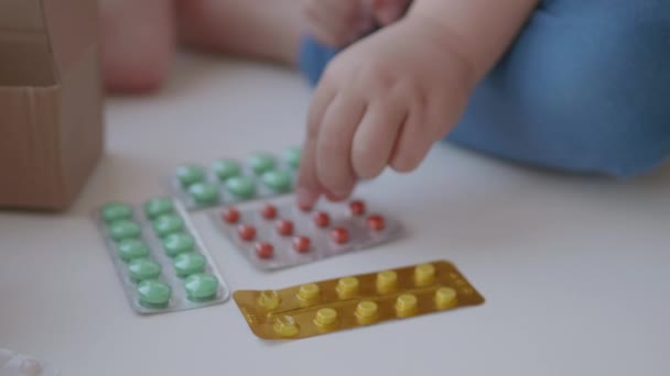 Peuter zit op vensterbank en speelt met versnippering pillen zonder ouders controle. Gevaarlijke situatie met kleine jongen. Geneesmiddelen zijn vrij beschikbaar voor kinderen. — Stockvideo