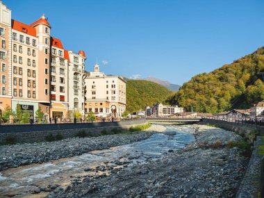 SOCHI, Rusya - 13 Ekim 2018. Rosa Dolina 'daki Mzymta nehri seti. Sochi yakınlarındaki ünlü Rosa Khutor Alpine Kayak Tesisi. Turistler Altın Lale Oteli 'nin yakınında yürüyor.