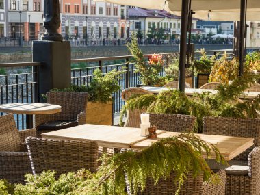 Mzymta nehir kıyısındaki kafede masa, sandalye ve saksı ağaçları. Rosa Dolina 'nın temiz ve bakımlı sokakları, Soçi, Rusya yakınlarındaki ünlü Rosa Khutor Alpine Kayak Resort' un bir parçası..