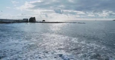 Martı kayanın üzerinde oturur. Soçi Limanı, Rusya. Kayalıklardaki martı siluetleri ve sakin deniz sörfleri..