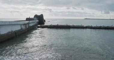 Martılar paslı korkuluklarda otururlar. Gün ışığında sakin deniz sörfü, Sochi, Rusya.