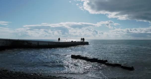 부두에서 검은 바다 사진을 찍는 사람들의 실루엣. 대낮에 바다를 횡단하는 엄청 난 파도, 러시아의 소 치. — 비디오