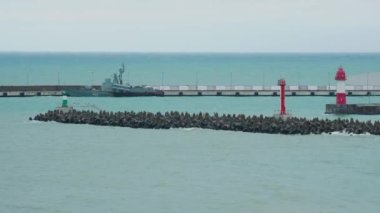 SOCHI, Rusya - Şubat 05, 2020. Martılar ve karabataklar dalgakıranların üzerinde otururlar. Bulutlu arka planda deniz feneri. Soçi Limanı, Rusya.