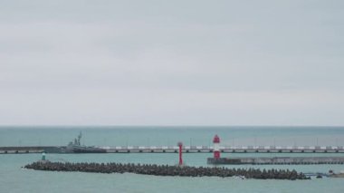 SOCHI, Rusya - Şubat 05, 2020. Martılar ve karabataklar dalgakıranların üzerinde otururlar. Bulutlu arka planda deniz feneri. Soçi Limanı, Rusya.