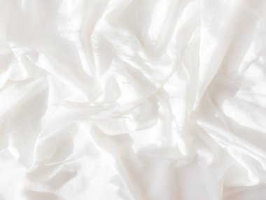 Beyaz buruşuk çarşaflı arka plan. Kopyalama alanı olan yumuşak çarşaflar. Konforlu evin yatak odasındaki dağınık yatak. Güneş ışığı ve gölge.