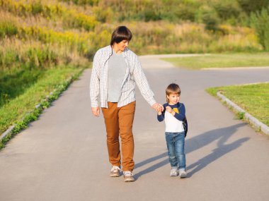 Baba oğlunu okula götürür. Yaz tatilinden sonra okula dönüyorum. Baba ve çocuk el ele yürüyorlar. Aile zamanı, moral desteği..