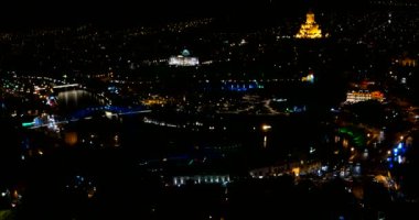 Gürcistan 'ın Tiflis başkentinin gece manzarası. Metekhi Kilisesi Kutsal Üçlü Katedrali Sameba ve Başkanlık İdaresi gece aydınlatma ve hareket halindeki arabalarla