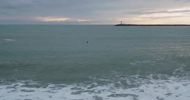 Les mouettes et les cormorans sont assis sur le brise-lames. Phare sur fond de coucher de soleil. Port de Sotchi, Russie. — Video