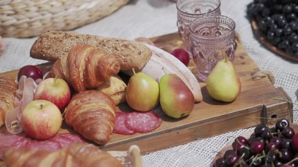 Пикник на открытом воздухе - фрукты и выпечка на деревянном подносе и скатерти. Еда для вечеринки на свежем воздухе. — стоковое видео