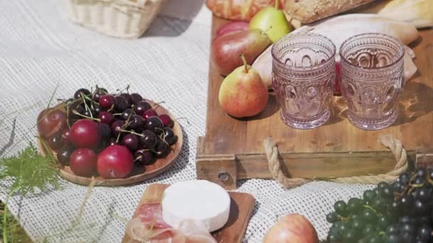 Picknick in de openlucht - fruit en gebak op houten dienblad en tafelkleed. Vers voedsel voor outdoor party. — Stockvideo