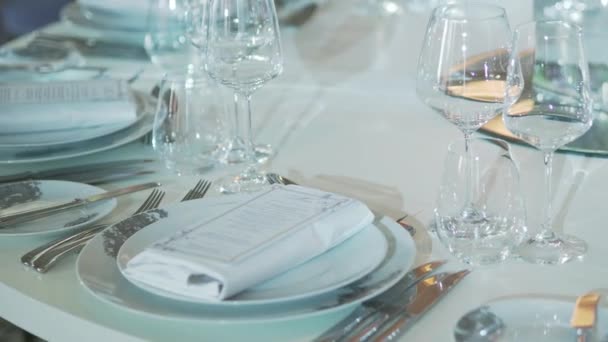 Mesa servida para banquete con cubiertos, copas de vino y servilletas. Decoraciones de color pastel. — Vídeos de Stock