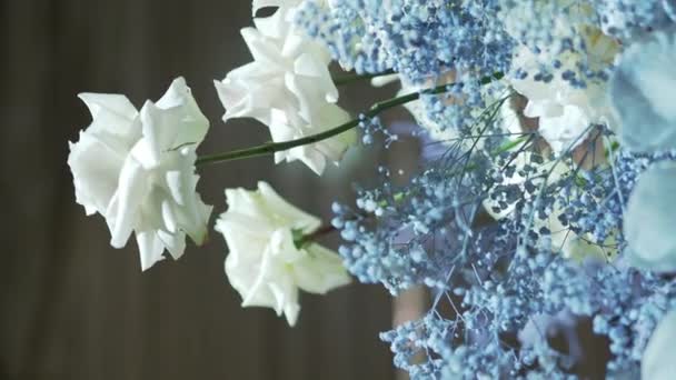 Weiße Rosen und blaue Gipsophila in einer Vase auf einem Tisch, der für eine Party dekoriert ist. Natürliche Dekoration. — Stockvideo