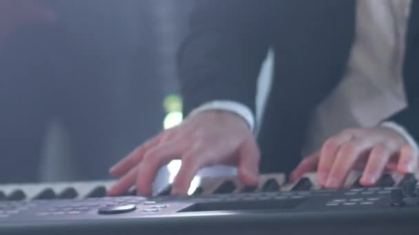 L'homme en costume joue du synthétiseur électrique à six cordes au concert. Gros plan des mains musicales à la fête avec des lumières disco stroboscopiques. — Video