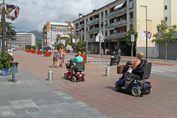 Calella, İspanya - 08 Eylül 2014: Calella içinde sokakta insanlarla elektrikli tekerlekli sandalye üzerinde yolculuk