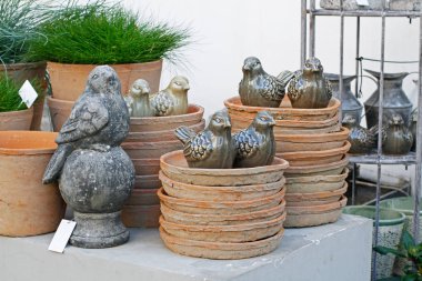 Taş ve seramik kuşlar, yeşil çim saksı ve bir çiçek dükkanında eski yemekleri