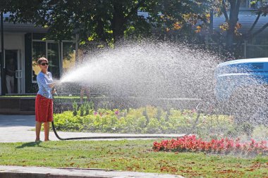 Beyaz Rusya, Gomel-07 Ağustos 2013: Çiçeklik Gomel hortumu ile sulama kadın