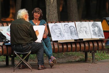 Minsk, Beyaz Rusya - 09 Ağustos 2013: Sanatçı Minsk şehir parkı bir kadın portresi çizer