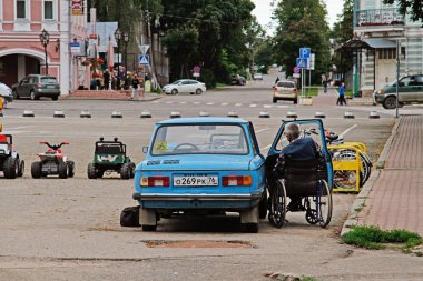 Uglich, Rusya Federasyonu - 02 Ağustos 2015: Eski arabada Zaporozhets Gaz 968 Uglich, yaşlı bir adam tekerlekli sandalyede yanındadır