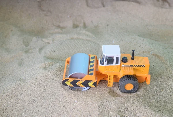 Car toy road roller construction equipment on sand background