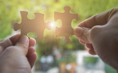 İki elim iki parçalı bulmaca parça güneş ışığı etkisi ile bağlanmaya çalışıyor. İş çözümleri, başarı ve stratejisi kavramı
