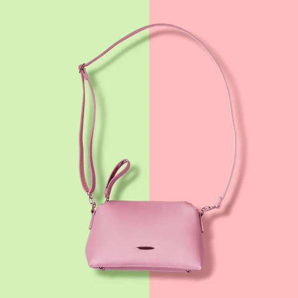 Ladies pink pastel handbag with long strap on pink background