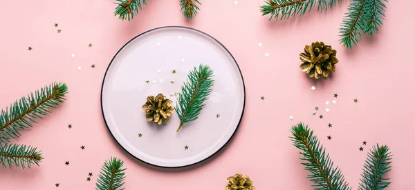 Christmas natural table setting. White plate and confetti on pink background, banner format