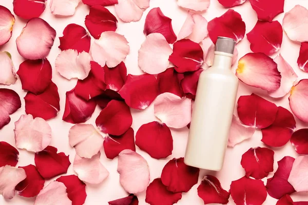 Bottle with natural cosmetic product on a background of rose petals. Spa concept.