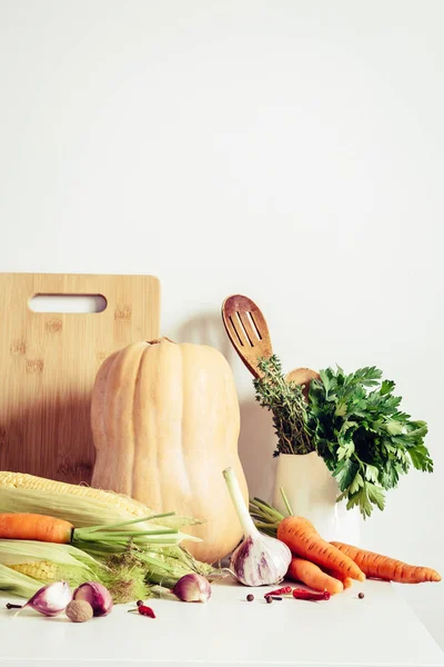 Autumn vegetables and kitchen utensils on table wall background. Seasonal food concept