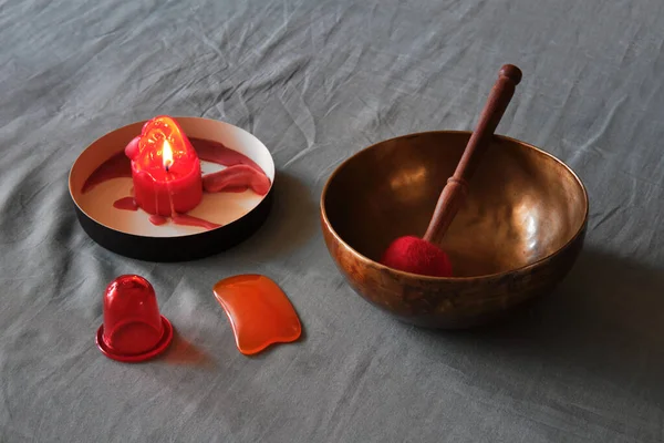 Massage items: oil, singing bowl, vacuum can and scented candle on textile linen background