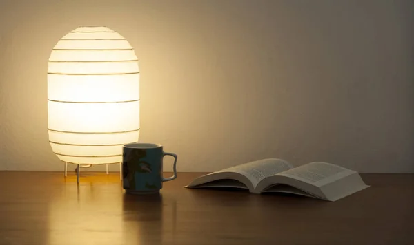 Книга с лампами и кружка на столе — стоковое фото