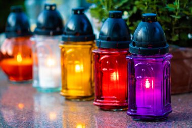 Ruhlar Günü 'nde bir mezarda yanan renkli mumlarla dolu sıra.