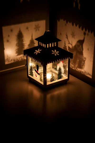 Christmas tea light candle lantern with snowman cast shadows of christmas trees and snow flakes
