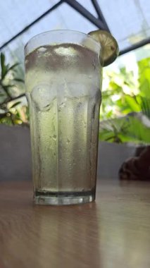 Bardakta buz küpleriyle taze limon, ferahlatıcı narenciye içeceği sıcak günler için mükemmel, tazeliği, doğal aromayı ve yaz içeceğini simgeliyor..