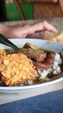 Geleneksel Endonezya rawon çorbası tempo ile servis edilir. Zengin siyah et, taze et ve mayalanmış soya sosu karışımı vurgulanır..