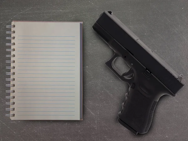 Üstten görünüm defter ve silah okuldaki masada. (önleme kavramı)